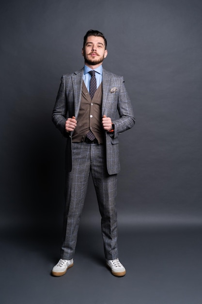 Full length portrait of a fashion male model over grey background. Looking at camera.