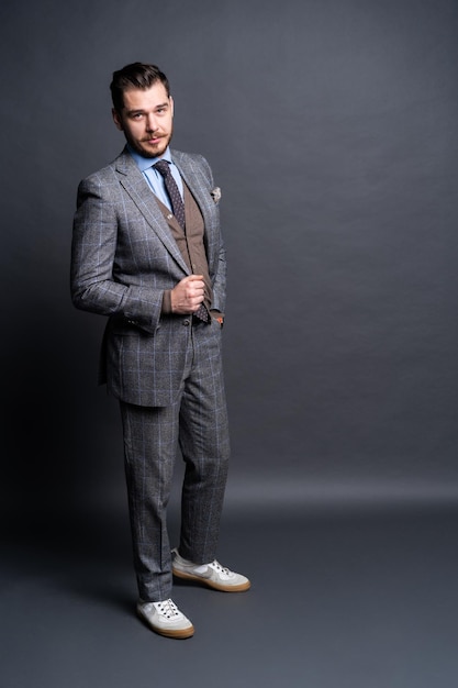 Full length portrait of a fashion male model over grey background. Looking at camera.