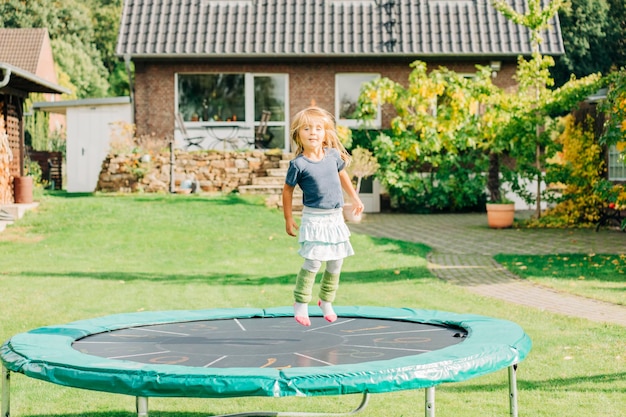 Photo full length portrait of girl jumping on trampoline outdoors