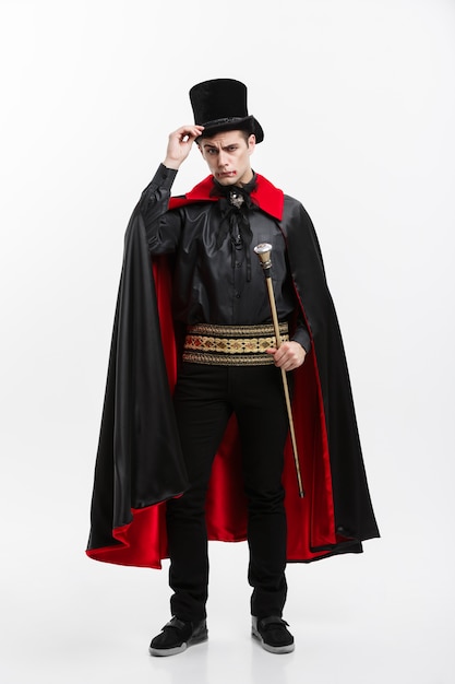 Foto ritratto integrale del vampiro caucasico bello in costume nero e rosso di halloween.