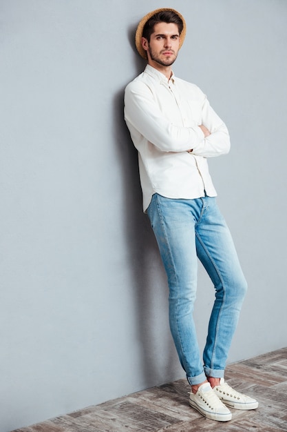 Full length portrait of handsome man standing with arms folded isolated