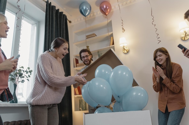 Full length portrait of happy couple holding boy or girl reveal party over balloons