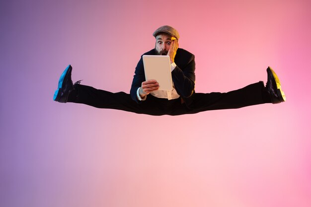 Photo full length portrait of happy jumping man in neon light and gradient background