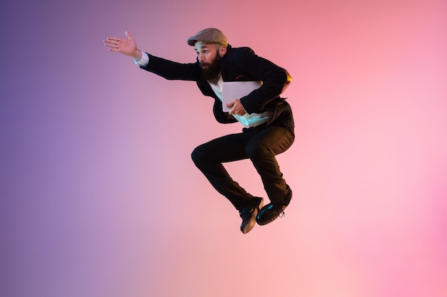 Полный портрет счастливого прыгающего человека в неоновом свете и градиентном фоне