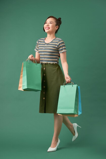 Full length portrait of a happy pretty girl holding shopping bags while walking