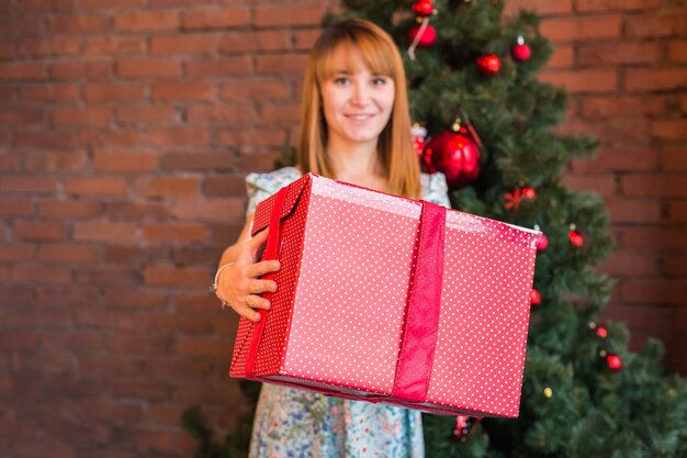 Full length portrait of happy young woman decorating christmas tree with christmas ball.