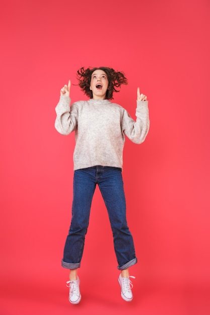 Full length portrait of a happy young woman isolated over pink, presenting copy space