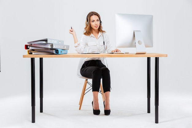 Full length portrait of a happy young woman working with computer in call center over white background