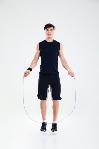 Full length portrait of a man jumping with skipping rope isolated