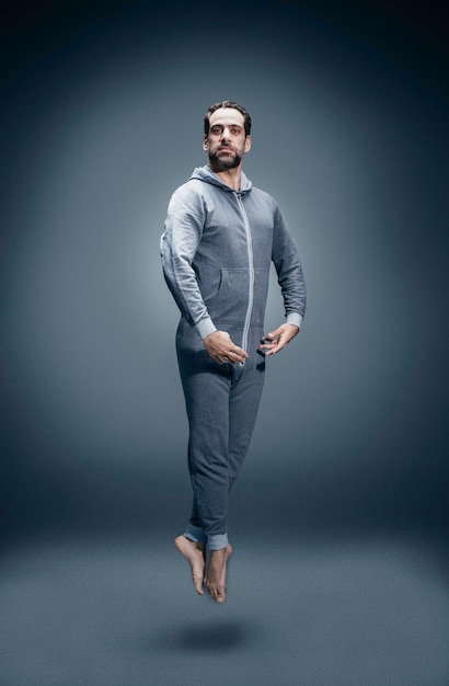 full length portrait of man levitating against gray background