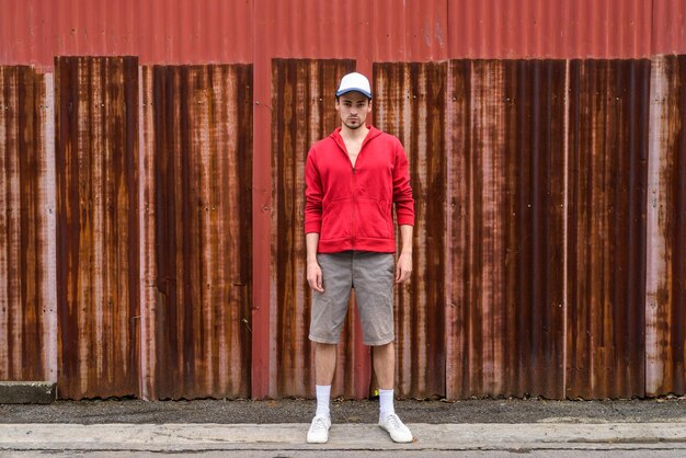 Foto ritratto a tutta lunghezza di un uomo in piedi contro un muro rosso