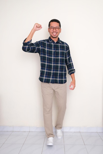 Full length portrait of a man walking towards camera with fist clenched showing optimism