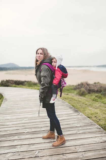 Photo full length portrait of mother carrying baby boy on boardwalk