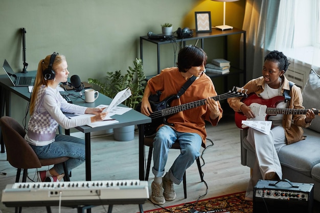 Full length portrait of music band writing songs together and playing musical instruments in studio