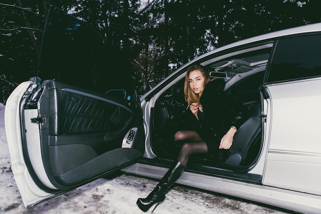 写真 冬の間車に座っている若い女性の全長の肖像画