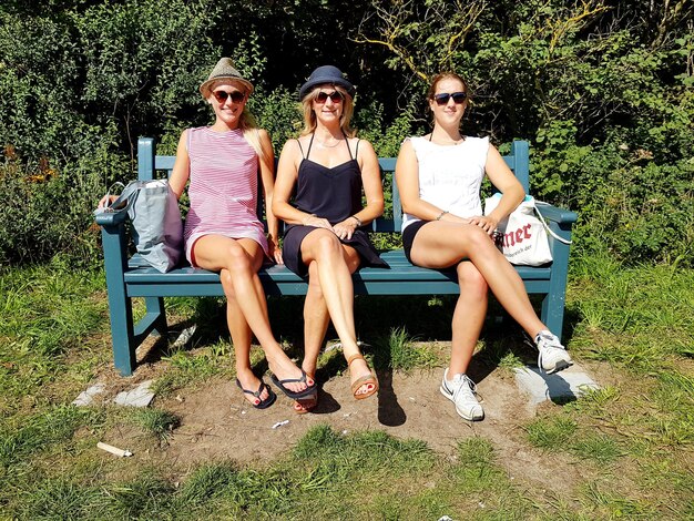 写真 ベンチに座っているサングラスを着た若い女性の全長肖像画