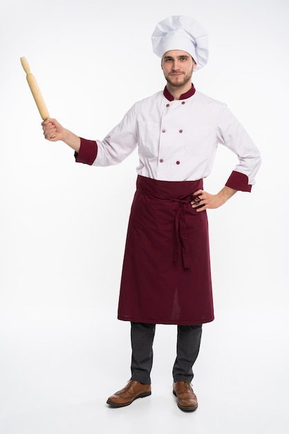 Full length portrait of positive toothy chef cook in beret, white outfit having tools in crossed arms looking at camera isolated on white background