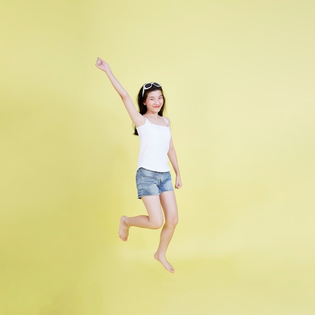 Портрет красивой азиатской девушки в полный рост, улыбаясь и прыгая