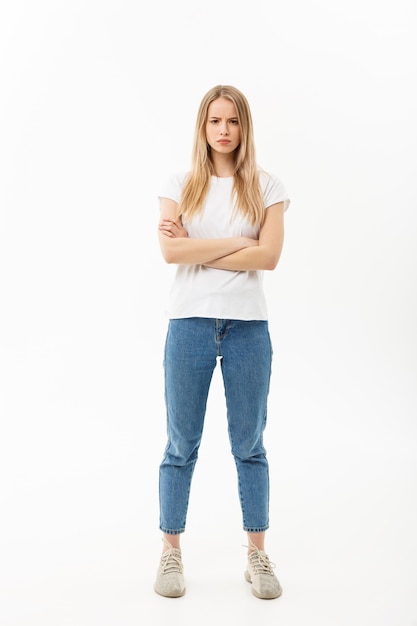 Ritratto integrale di una donna caucasica abbastanza giovane che indossa jeans e che sembra turbato con le sue braccia attraversate