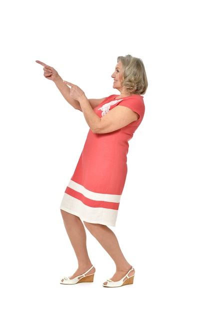 Full length portrait of senior woman pointing on white background