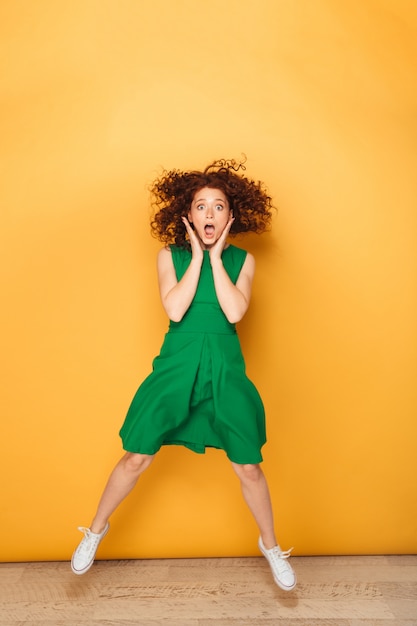 Full length portrait of a shocked redhead woman