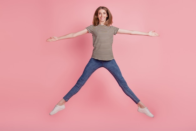 Full-length portrait of slim young woman happy positive smile have fun jump up isolated over pink color background