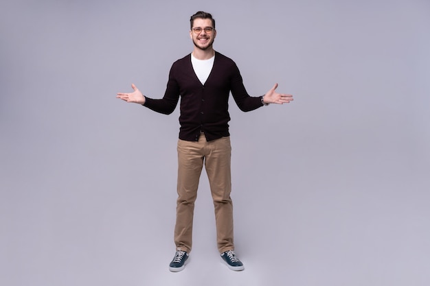 Full length portrait of a smiling casual man standing isolated on a gray background.