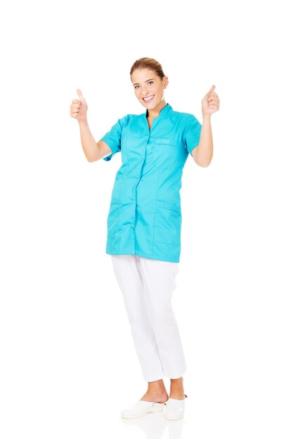 Full length portrait of smiling nurse showing thumbs up sign on white background