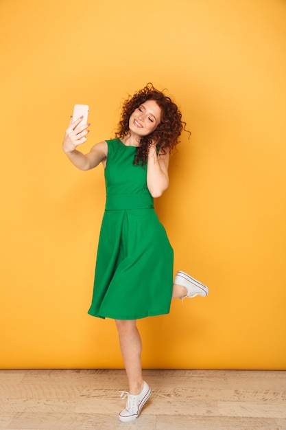 Full length portrait of a smiling redhead woman in dress