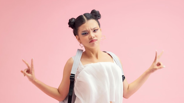 Full length portrait of a smiling woman with backpack standing on pink background and looking at camera