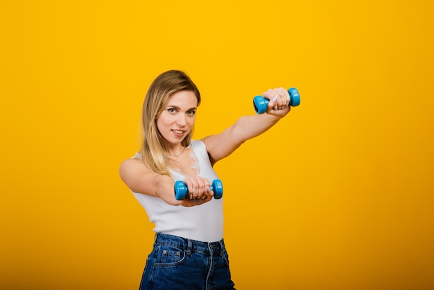 Ritratto integrale di giovane ragazza sorridente di forma fisica in perfetta forma, girato in studio, sfondo giallo