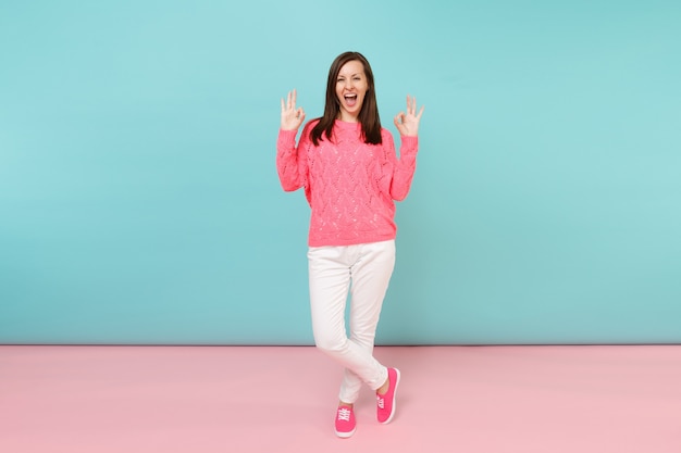 Photo full length portrait of smiling young woman in knitted rose sweater, white pants posing