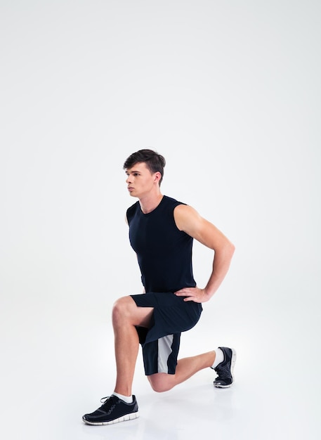 Full length portrait of a sports man doing warm up exercises isolated