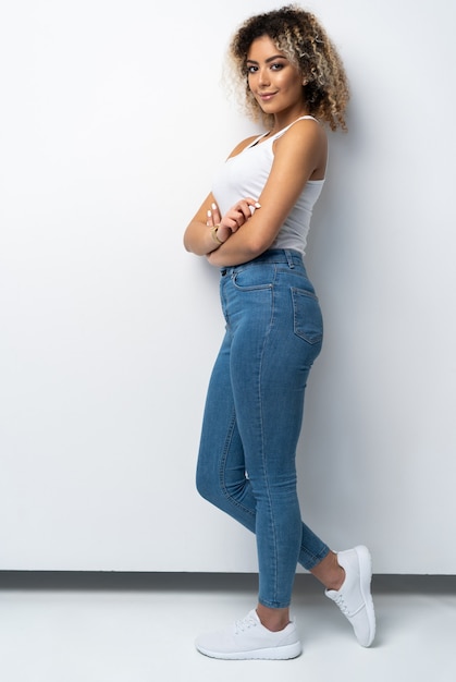 Foto ritratto integrale di giovane donna nera alla moda in piedi su sfondo bianco.