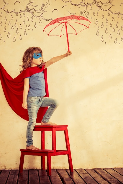 Full length portrait of superhero kid against grunge wall background