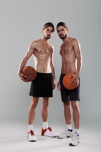 Full length portrait of a two muscular shirtless twin brothers