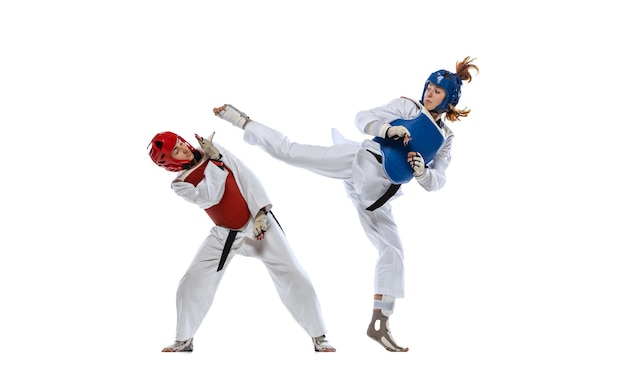 Full-length portrait of two professional taekwondo feale athletes fighting isolated over white background