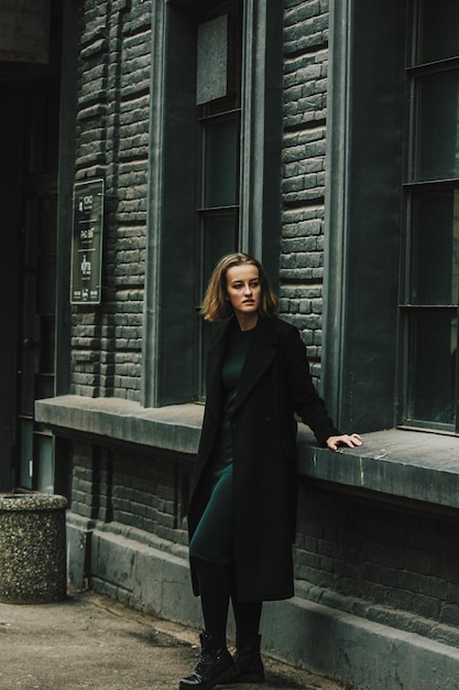 full length portrait of woman standing against building