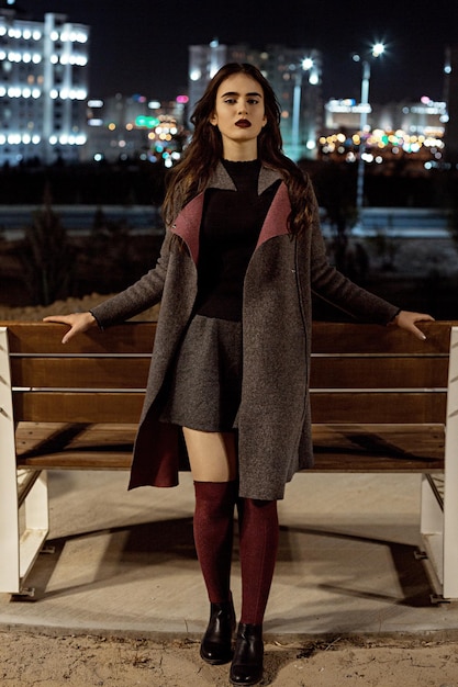 full length portrait of woman standing against illuminated building