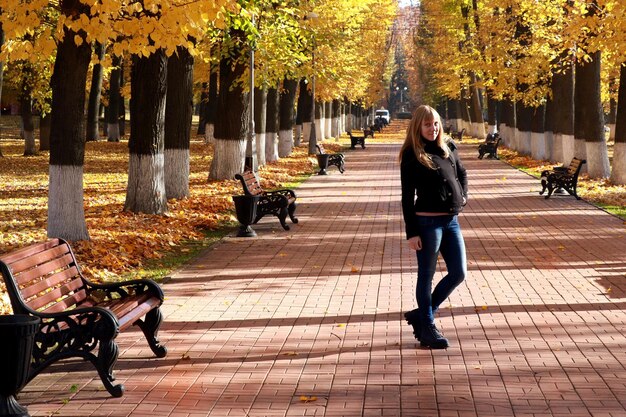 Foto ritratto a tutta lunghezza di una donna in piedi sul sentiero nel parco durante l'autunno