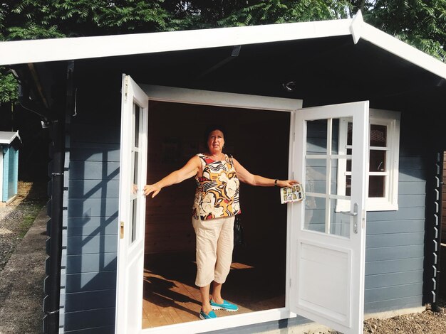 Photo full length portrait of woman standing at house doorway