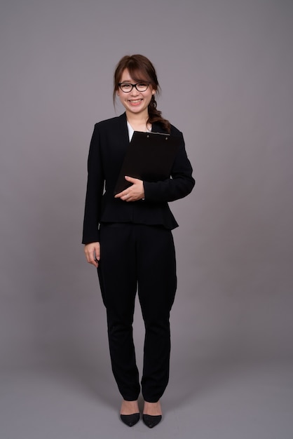 Full length portrait of young Asian businesswoman standing