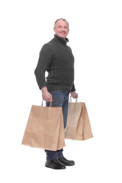 Full length portrait of a young casual man holding shopping bags isolated against white background