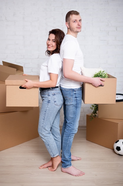 Full length portrait of young couple holding cardboard boxes ready to moving day