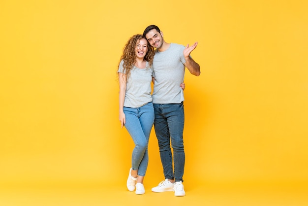 Full length portrait of young happy interracial couple in isolated yellow studio background