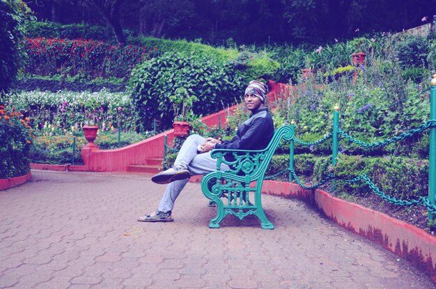 Full length portrait of young man sitting against trees