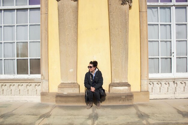 Full length portrait of young man sitting in city