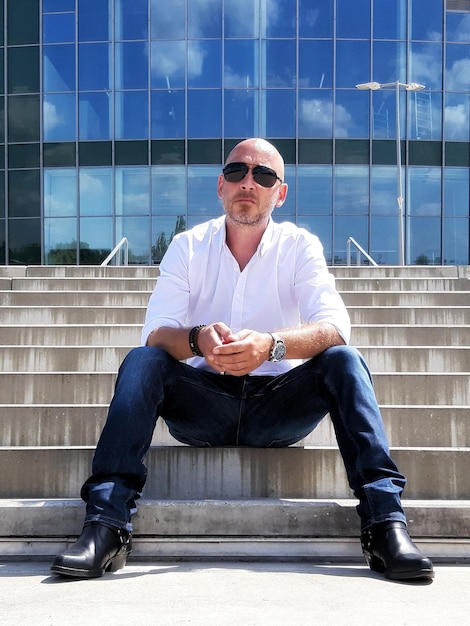 Full length portrait of young man sitting outdoors