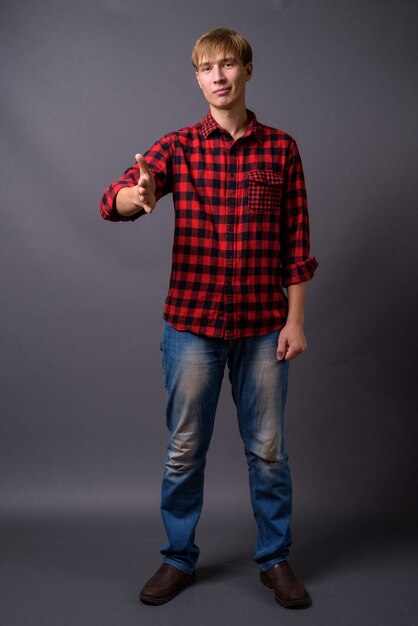 Full length portrait of young man standing against gray background