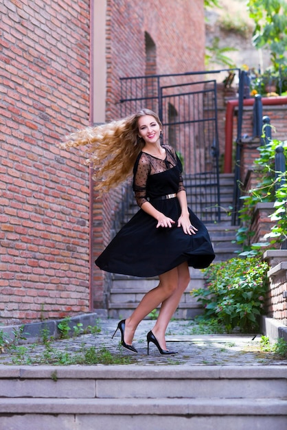 Full length portrait of young woman against brick wall